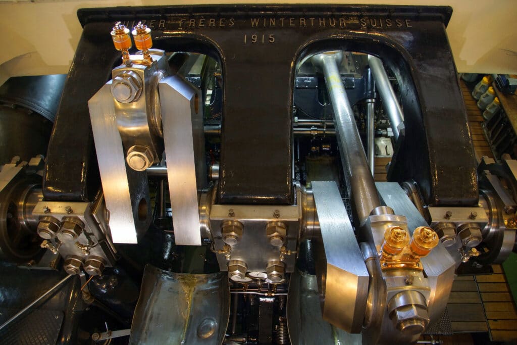 Machine à vapeur compound à double expansion de 1915, fabriquée par Sulzer Frères Winterthur, avec cylindres en acier poli, bielles et graisseurs en laiton, moteur historique équipant les bateaux à roues de la CGN sur le lac Léman